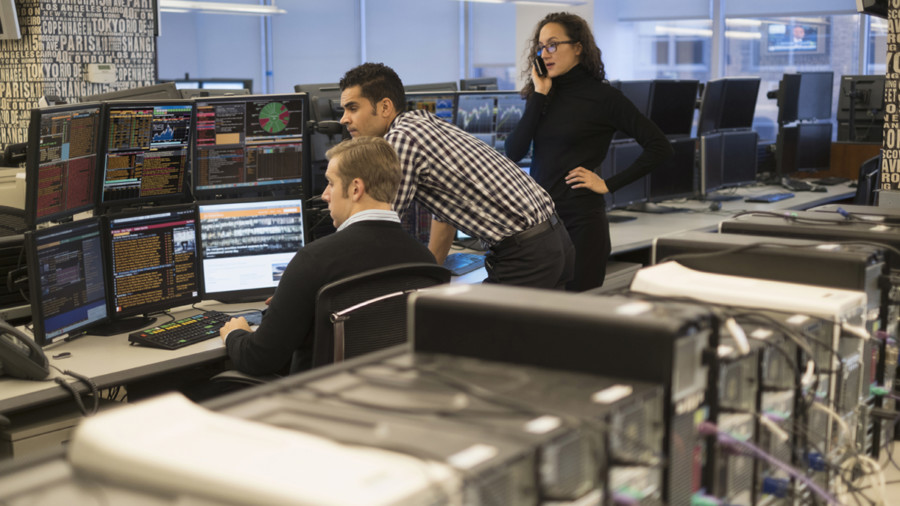 Traders looking at computer screens near a large bank of computers