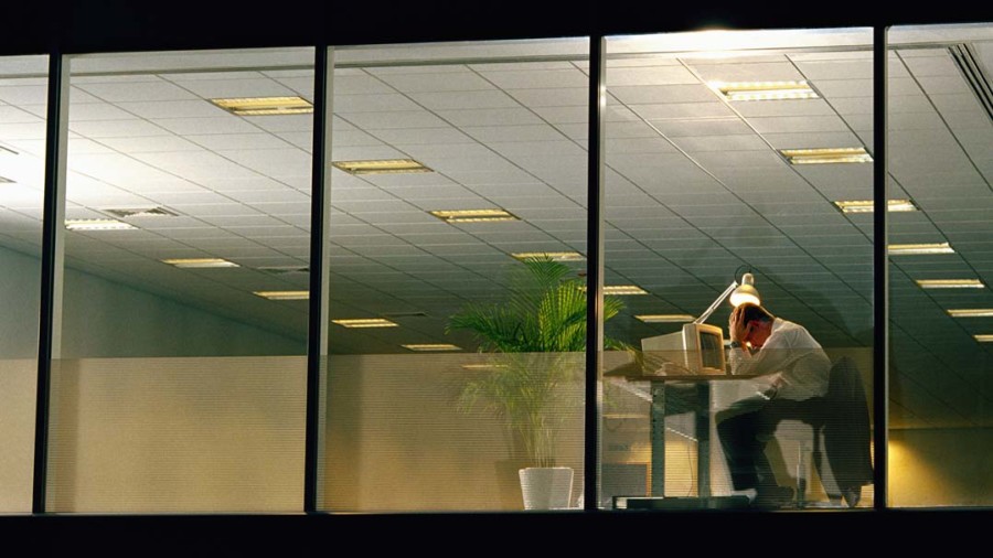 Man in office late at night, head in hands