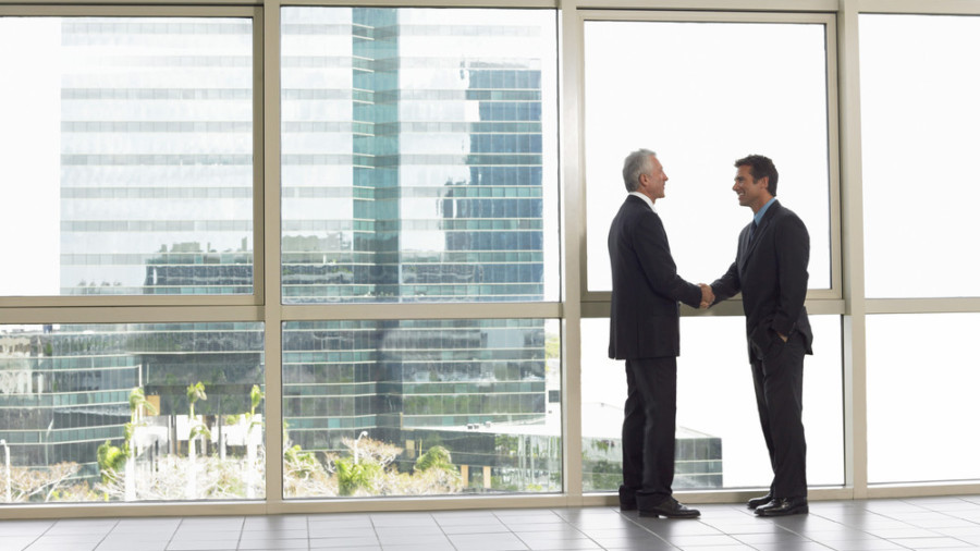 Two business men shaking hands in window