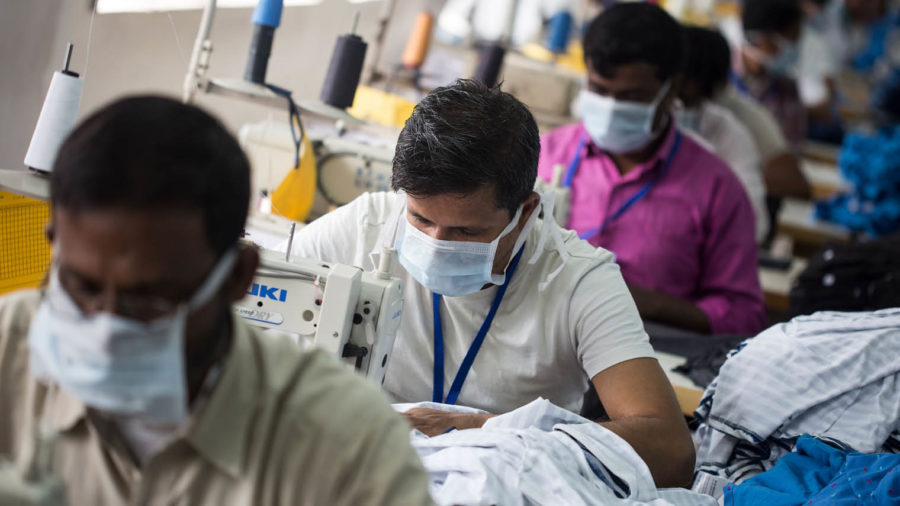 people sewing in factory, wearing face masks