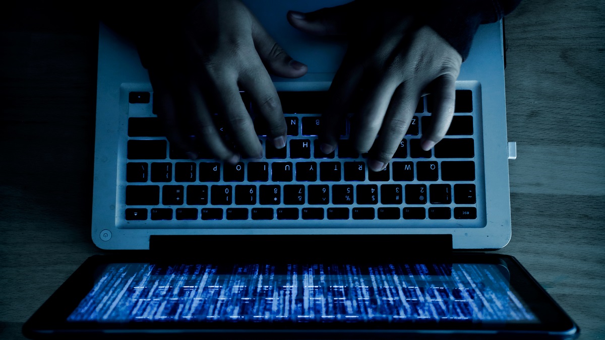 A computer programmer or hacker prints a code on a laptop keyboard to break into a secret organization system. Internet crime concept.