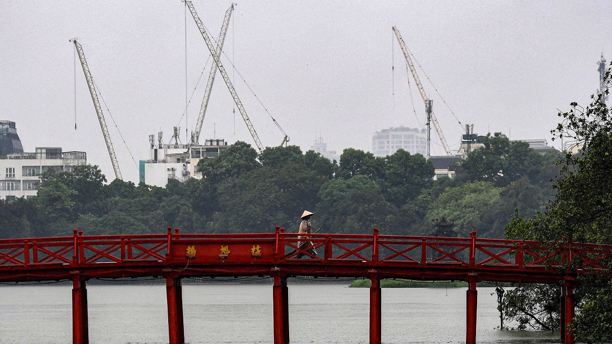 A woman walks during rainfall on Huc Bridge over the Hoan Kiem Lake in downtown Hanoi on August 12, 2022. (Photo by Nhac NGUYEN / AFP) (Photo by NHAC NGUYEN/AFP via Getty Images)